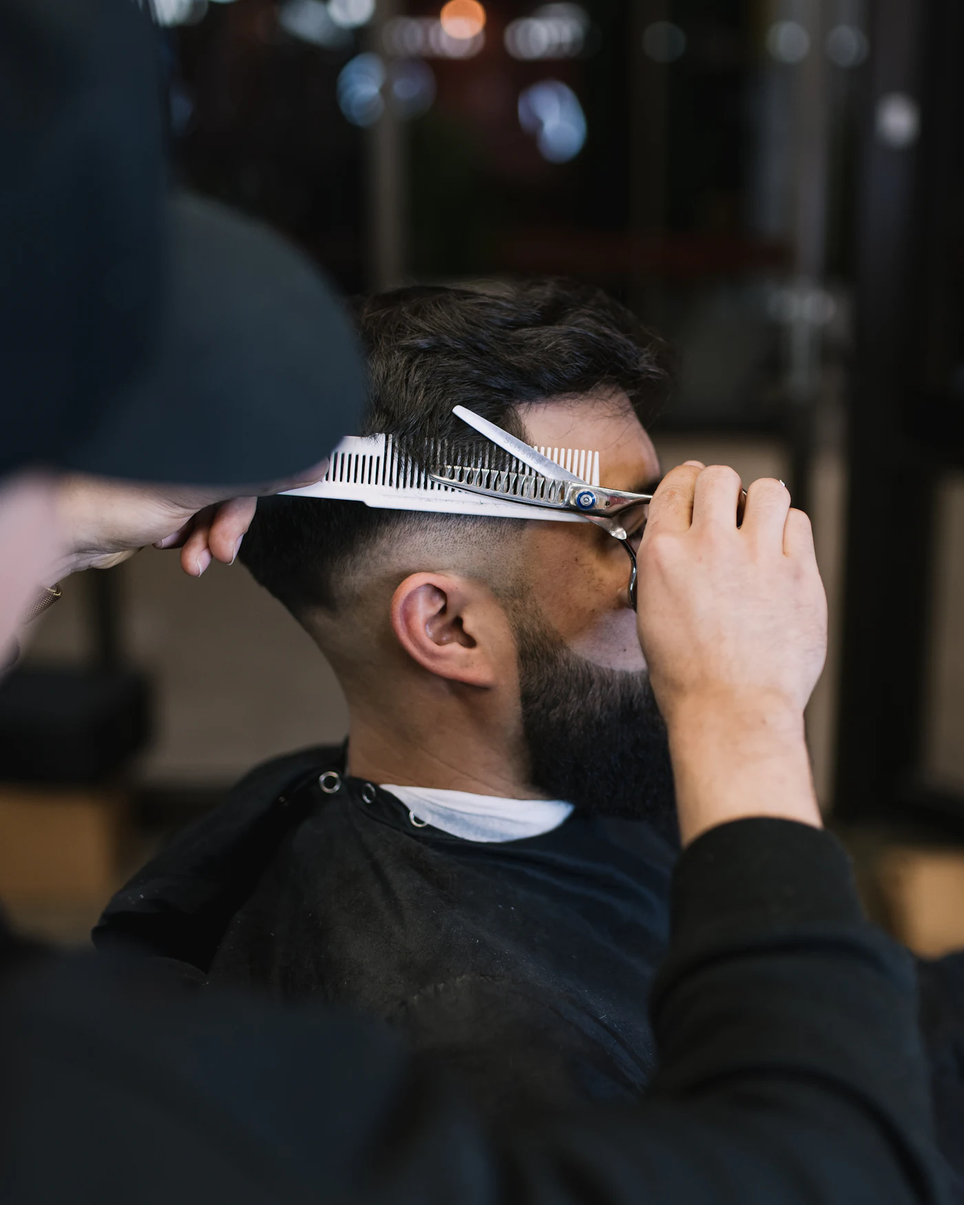 Un barbier coupe les cheveux d’un client aux ciseaux