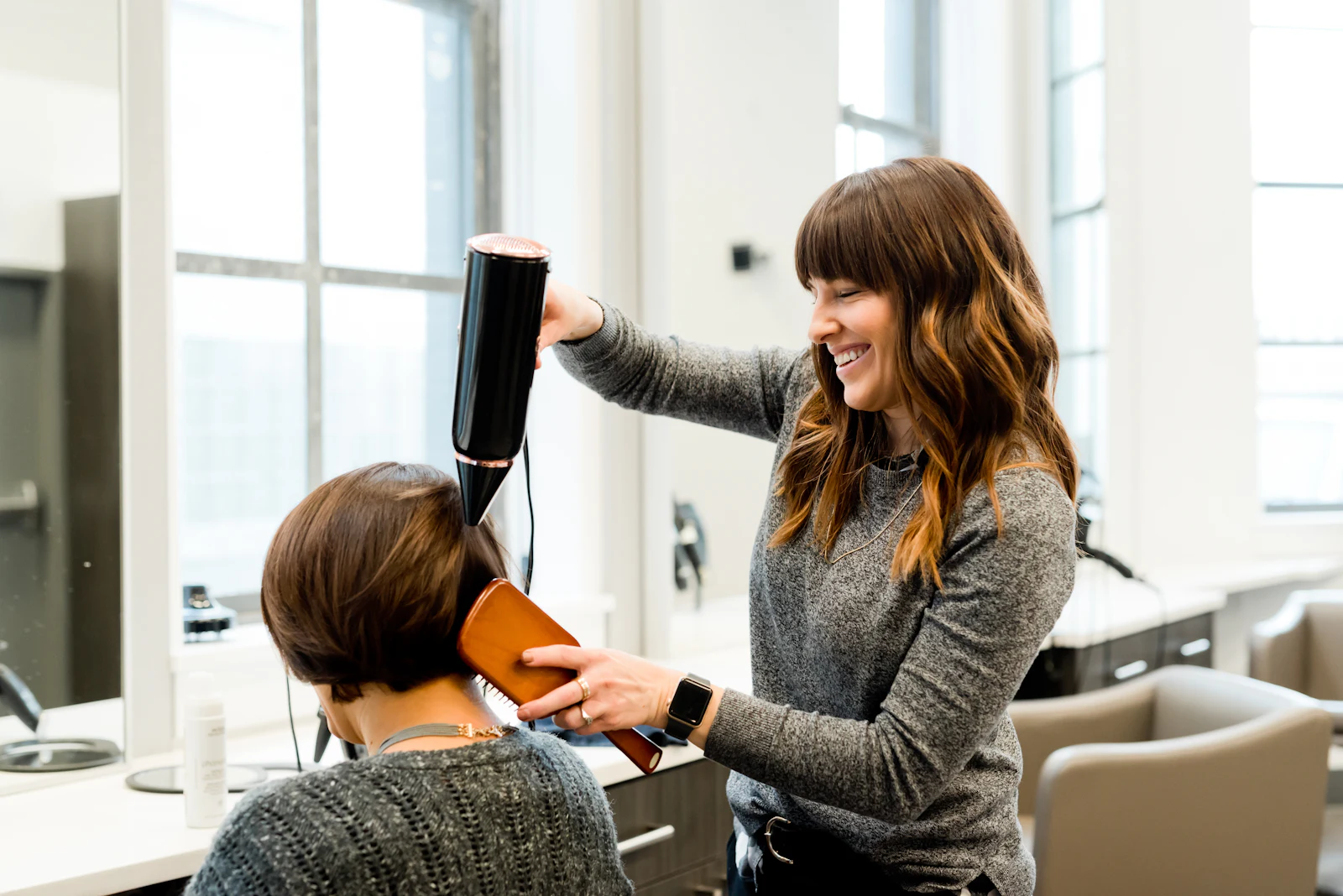 Une coiffeuse fait un brushing à une cliente